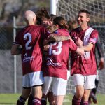 A group of Tathra United football players gather on the field, smiling and patting each other on the back after a successful play.