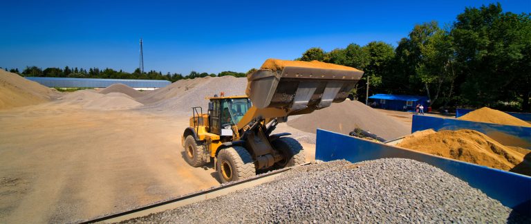 A loader lifting a full bucket at the quarry bins.