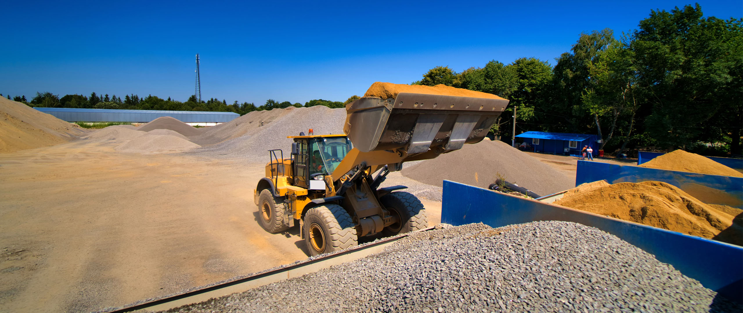 A loader lifting a full bucket at the quarry bins.