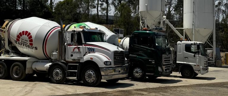 Three Stafford’s trucks lined up in front of large concrete silos at the batching plant.