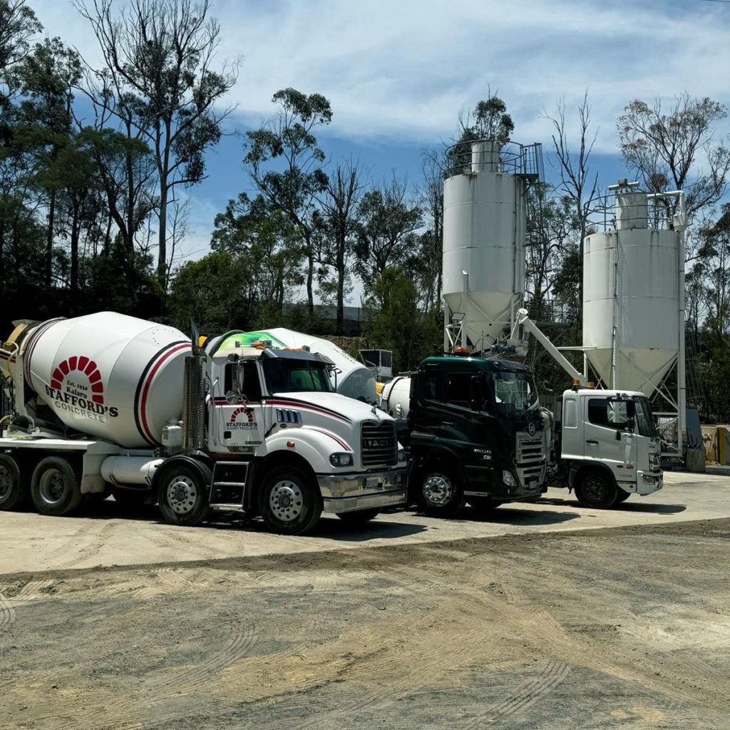 Three Stafford’s trucks lined up in front of large concrete silos at the batching plant.